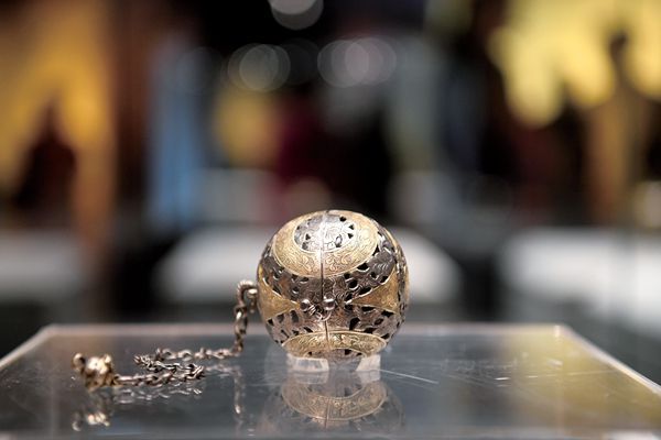 A recently uncovered silver censer sitting on top of a glass tray. 